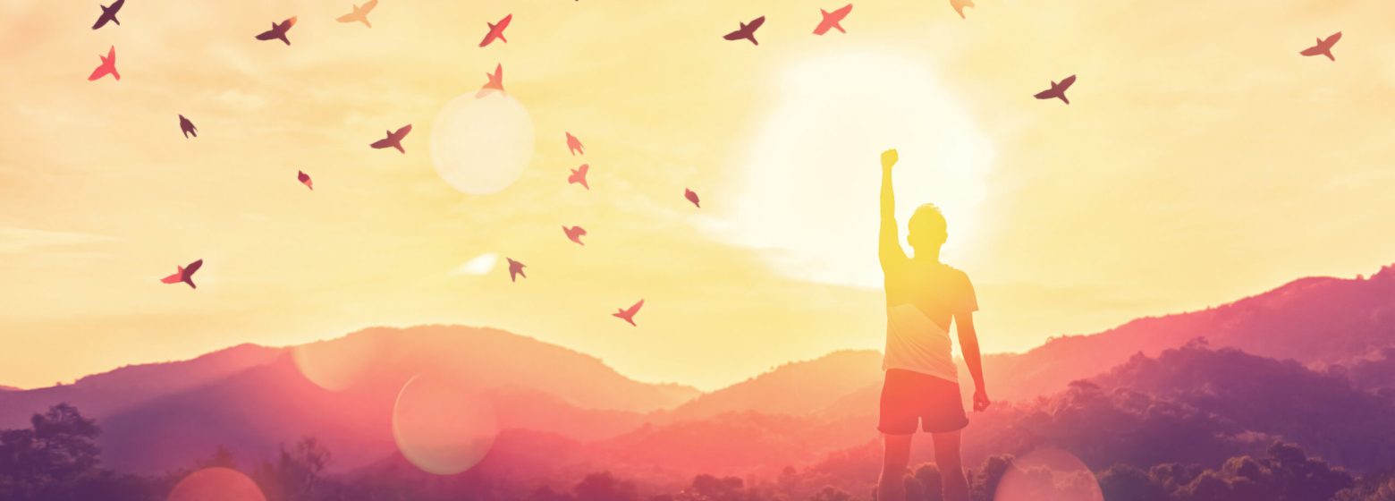 Freedom feel good and travel adventure concept. Copy space of silhouette man rising hands on sunset sky at top of mountain and bird fly abstract background. Vintage tone filter effect color style.